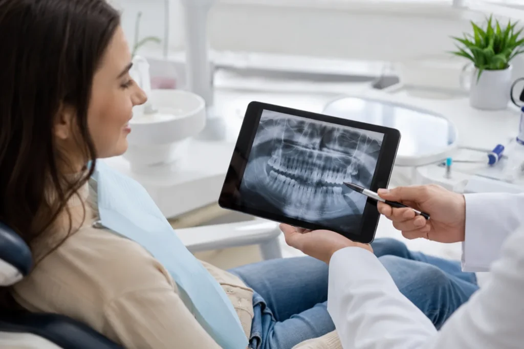 Dr. Abid showing a patient her panoramic dental X-ray on a tablet and explaining the findings